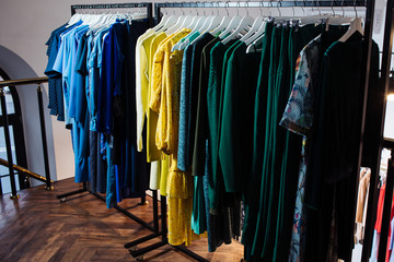 Close-up view of various stylish clothes hanging on hangers in boutique. Clothes