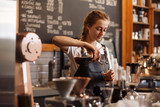 Professional barista preparing coffee using chemex pour over coffee maker and drip kettle. Young woman making coffee. Alternative ways of brewing coffee. Coffee shop concept.