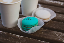 Two Coffee In Paper Cups, Two Macaroons Of Mint And White Color On A Wooden Vintage Table.