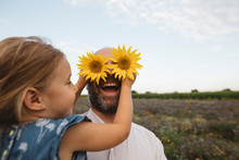 Daughter Covering Eyes Of Father With Sunflowers