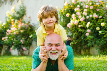 Cute boy with dad playing outdoor. Happy family Grandson hugs his grandpa on holiday. Happy grandfather and grandson relaxing together. Concept of friendly family.