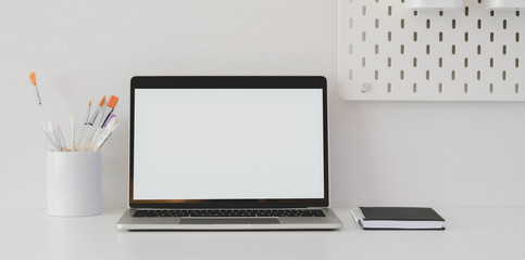 Minimal artist workspace with blank screen laptop computer and decorations