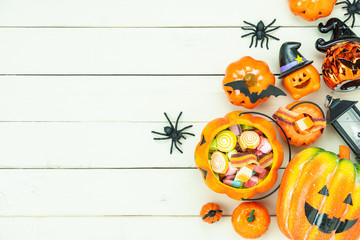 Table top view aerial image of decorations Happy Halloween day background holiday concept.Flat lay objects to party pumpkins and spider with candy sweet on white wooden wallpaper.Copy space for text.