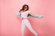 © ClaudiK - Inspired positive girl in white sneakers dancing on pink background. Gorgeous young female model with dark wavy hair jumping in studio. Not isolated. Copy space.