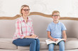 © stock28studio - Cute tutor in nice shirt and happy young boy wearing blue shirt sit on white sofa and look in camera with smile on faces