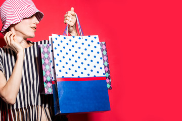 Wall Mural - Young woman with shopping bags over red background