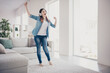 © deagreez - Full length photo of amazing lady listening favorite melody in modern earflaps dancing overjoyed in light room wearing jeans clothes apartment indoors