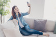 © deagreez - Photo of amazing lady telephone in hands making selfies for social network blog sitting comfy sofa wearing jeans clothes apartment indoors