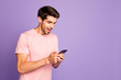 © deagreez - Profile side view portrait of his he nice attractive cheerful glad focused guy wearing pink tshirt holding in hands using digital device gadget isolated on violet purple lilac pastel color background