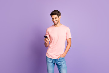 Poster - Portrait of his he nice attractive lovely cheerful cheery guy wearing pink tshirt holding in hands using 5g app cell isolated over violet purple lilac pastel color background