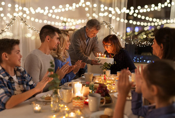 Sticker - celebration and family concept - happy grandmother blowing candles on birthday cake at dinner party at home