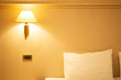© bdrvoloshin - Simple bulb lamp  hanging on wall near bed with white bedclothes. Bedroom interior.