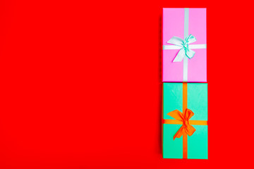 Sticker - colored boxes with ribbons on a red background. view from above.