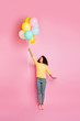 Vertical full body photo of cute nice girl with many baloons in hand feeling the wind become stronger and can be blown up to the sky isolated shiny color background