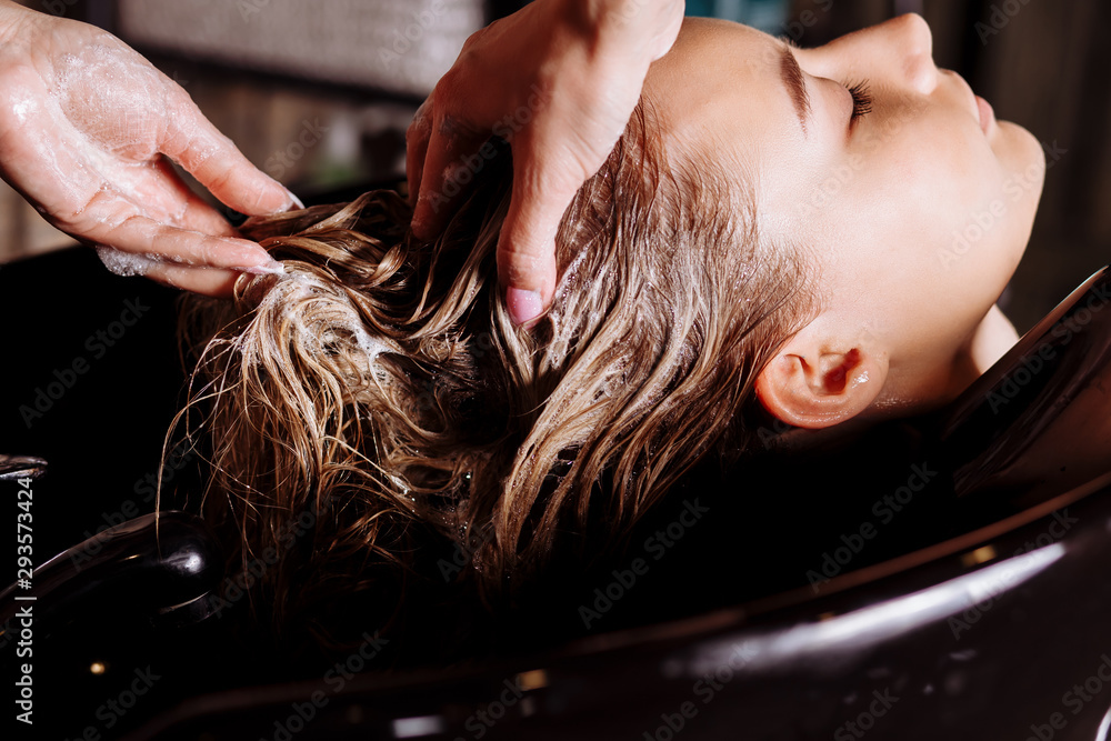 Beautiful woman washing hair in a hair salon - obrazy, fototapety, plakaty 