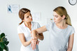 © LIGHTFIELD STUDIOS - chiropractor touching hand of attractive patient in grey t-shirt