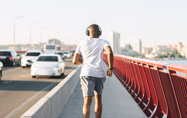 Wall Mural - Sporty black guy running along the bridge