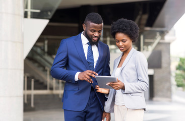 Business people using digital tablet together outdoors