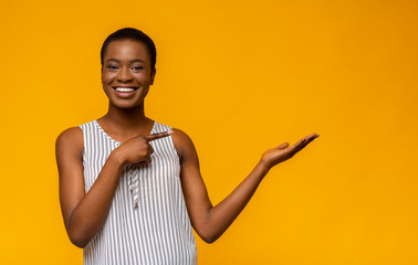 Wall Mural - Cute black girl pointing at empty space