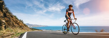 Mature Adult On A Racing Bike Climbing The Hill At Mediterranean Sea Landscape Coastal Road