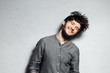 Portrait of young happy bearded guy with disheveled hair on grey background.