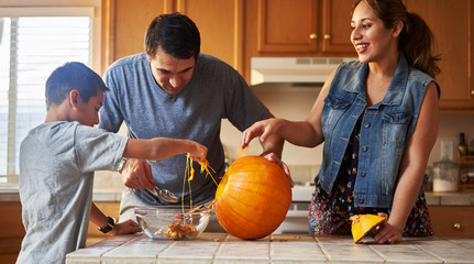 Wall Mural - hispanic american family carving pumpkin into jack o lantern at home