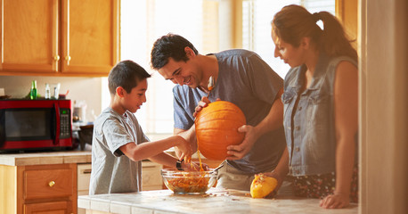 Wall Mural - hispanic american family carving pumpkin into jack o lantern at home