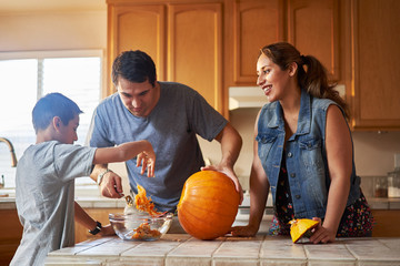 Wall Mural - hispanic american family carving pumpkin into jack o lantern at home