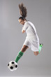 Young woman kicking soccer ball
