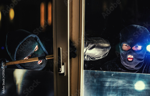 Fotomural Masked burglar with torch and crowbar breaking and entering into a house - shot
