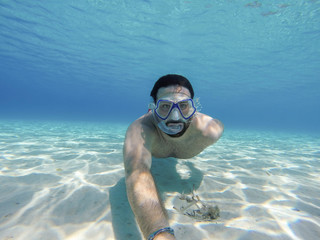 Young man swims in the sea - Millennial does snorkeling in the ocean in the summer