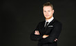 © Arunporn - Portrait of young smart and handsome business man in black suit standing on isolated black background.