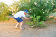 © Aliaksei Luskin - boy in a hat studies a cactus plant in hot climates.