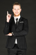 © Arunporn - Portrait of young smart and handsome business man in black suit standing on isolated black background.