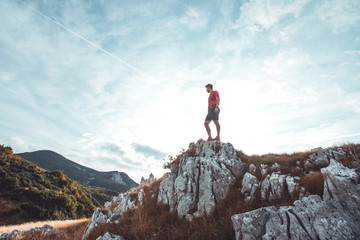 Young athletic man standing on the ridge. Trail running preparations for race.