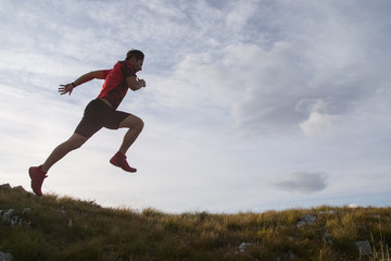 Trail running man jumping in the sky