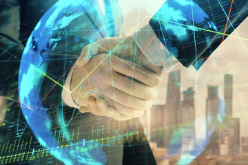 Double exposure of financial chart and world map on cityscape background with two businessmen handshake. Concept of international investment