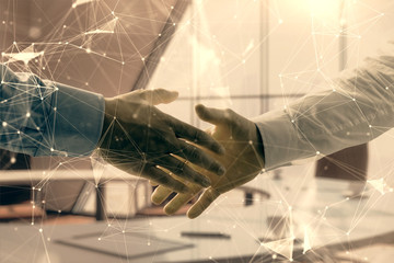 Multi exposure of tech theme hologram on office background with two men handshake. Concept of technology