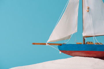 Poster - close up view of decorative ship in white sand isolated on blue