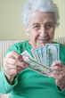 © berna_namoglu - A senior woman holding and giving American Dollars