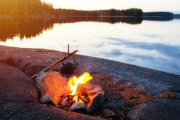 Wall Mural - Burning fire in nature near the lake. The campfire burns in the evening. Rest by the fire. Bonfire.