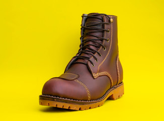 Wall Mural - Men fashion brown boot with pad leather steel toe isolated on yellow background. Fashion design by custom made for bikers.