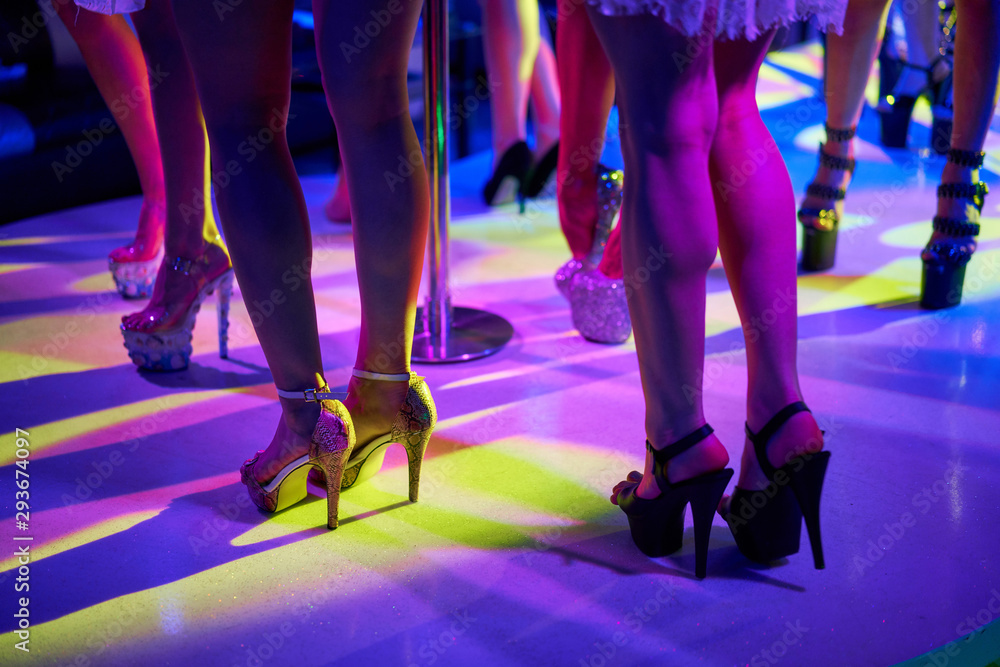 Young sexy woman pole dancing striptease with pylon in night club