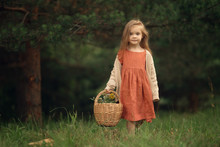 Female Kid Holding Wicker Basket With Flowers Standing In The Green Forest, Full Length Shot