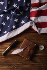 Sticker - top view of leather notebook, nib, telescope and compass on wooden surface with American national flag