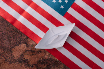 Sticker - top view of white paper boat on ancient world map with American national flag