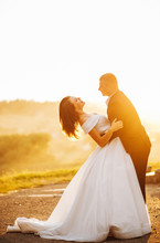 Sweet Groom Tilts His Bride In The Embrace At Sunset