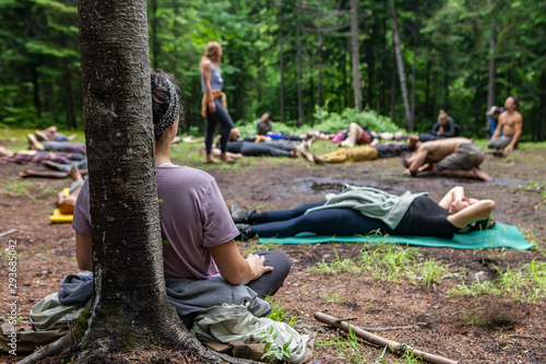 Diverse people enjoy spiritual gathering A multiethnic group of people of all ages are seen seeking enlightenment and mindfulness as they meditate in a forest clearing during a spiritual retreat.