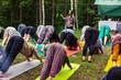Diverse people enjoy spiritual gathering A mixed group of people wearing colorful clothes practice sacred yoga in a forest clearing, seen in downward-facing dog pose (adho mukha svanasana).