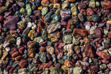 Colorful Rocks In A Glacier Lake During A Sunny Summer Day. Taken In Lake McDonald, Glacier National Park, Montana, USA.